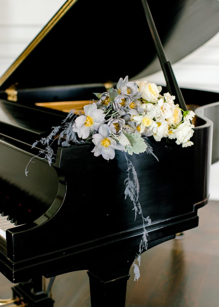 Black upright piano with white floral bouquet coming out